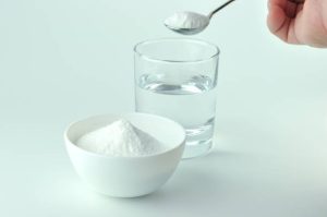 Baking soda, spoonful and glass of water.